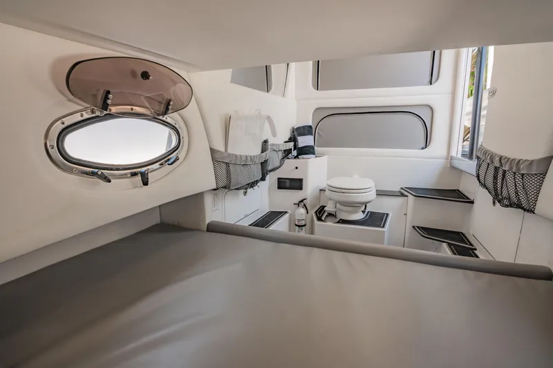  Yacht Photos Pics 2019 Nor-Tech 390 Sport cabin interior with bed, porthole, and compact bathroom.