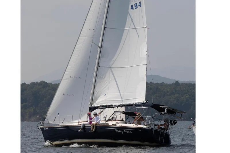  Yacht Photos Pics Sailing yacht Sabre 362, 1994 model, cruising on a calm lake with lush forest backdrop.