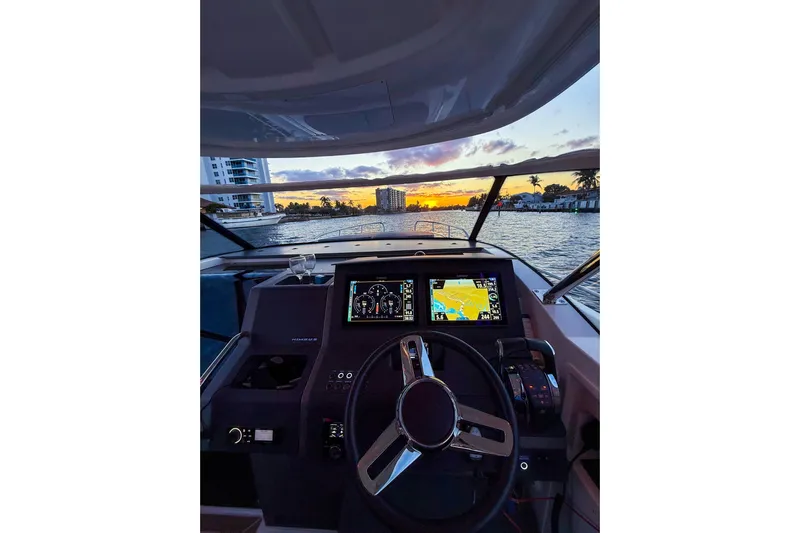  Yacht Photos Pics Cockpit view of 2022 Nimbus T11 boat at sunset, featuring navigation screens and steering wheel.