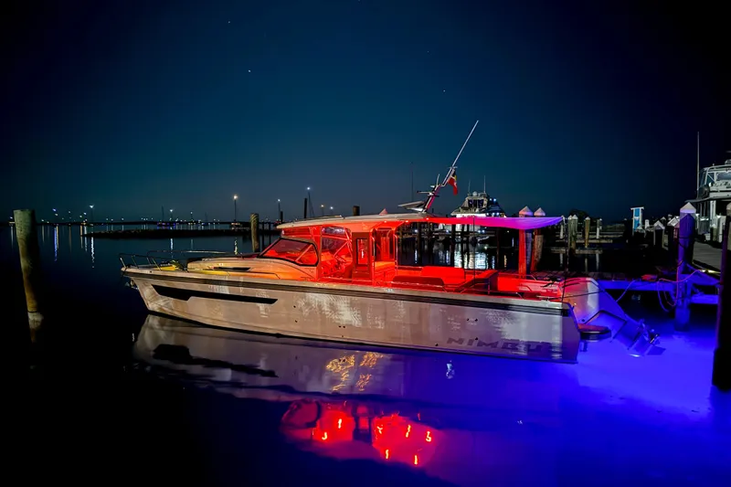  Yacht Photos Pics 2022 Nimbus T11 boat illuminated at night, docked with vibrant red and blue lights.