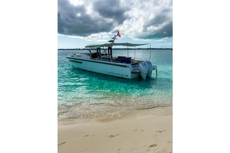  Yacht Photos Pics Nimbus T11 2022 boat anchored on turquoise water near sandy beach under cloudy sky.