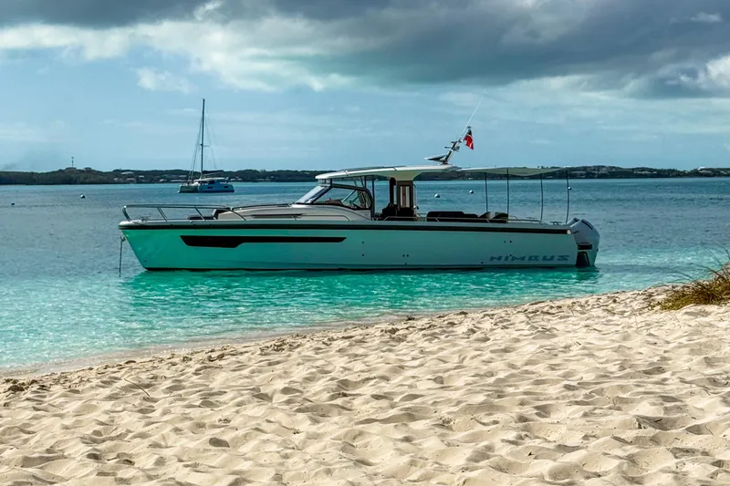  Yacht Photos Pics Nimbus T11 2022 boat anchored near sandy beach with turquoise water and cloudy sky.