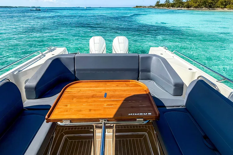  Yacht Photos Pics Luxurious Nimbus T11 boat interior with wooden table, surrounded by turquoise ocean waters.