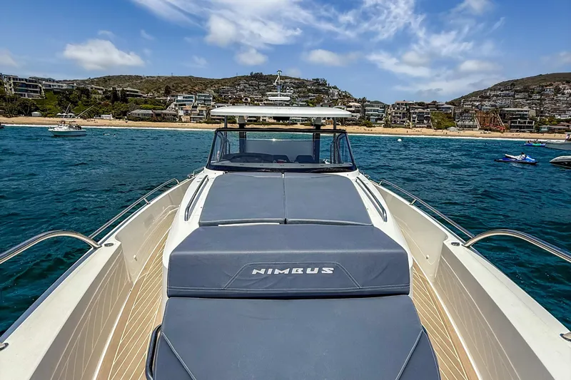  Yacht Photos Pics 2022 Nimbus T11 boat on water near a scenic coastal town.