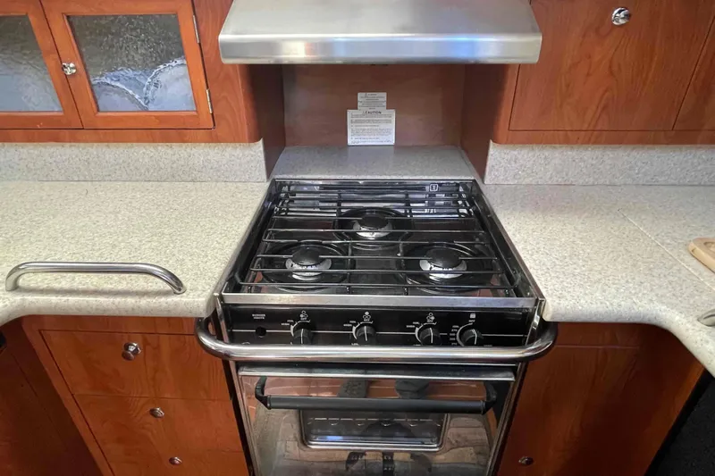 Snail'n Yacht Photos Pics Modern kitchen stove in 2010 Hunter 45 Center Cockpit yacht, featuring sleek countertops and wooden cabinetry.