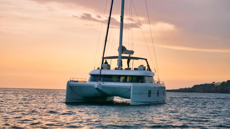 Feel The Blue Yacht Photos Pics 2018 Sunreef 60 catamaran sailing at sunset on calm waters.