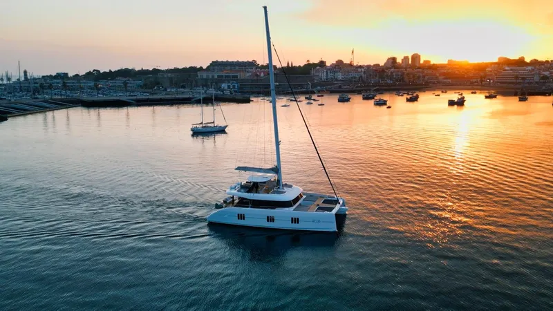 Feel The Blue Yacht Photos Pics Sunreef 60 yacht sailing at sunset in a tranquil harbor, 2018 model.