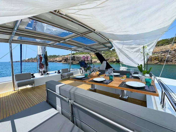 Feel The Blue Yacht Photos Pics Luxurious Sunreef 60 yacht deck with dining setup, overlooking serene coastal waters.