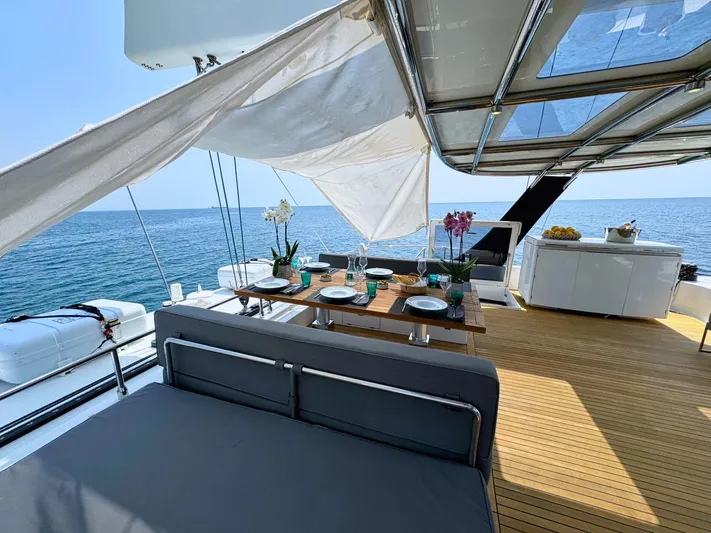 Feel The Blue Yacht Photos Pics Luxurious Sunreef 60 yacht deck with dining area, ocean view, and elegant decor, 2018 model.