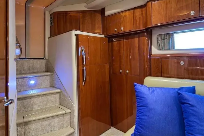 Still The One Yacht Photos Pics Luxurious interior of 2004 Sea Ray 550 Sundancer yacht with wooden cabinetry and blue cushions.