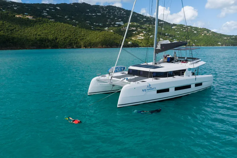 Aquanimity Yacht Photos Pics 2021 Dufour 48 catamaran in turquoise waters with snorkelers nearby.