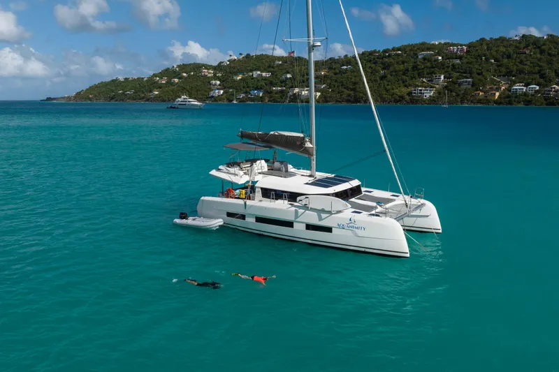 Aquanimity Yacht Photos Pics 2021 Dufour 48 catamaran anchored in turquoise waters with swimmers nearby.