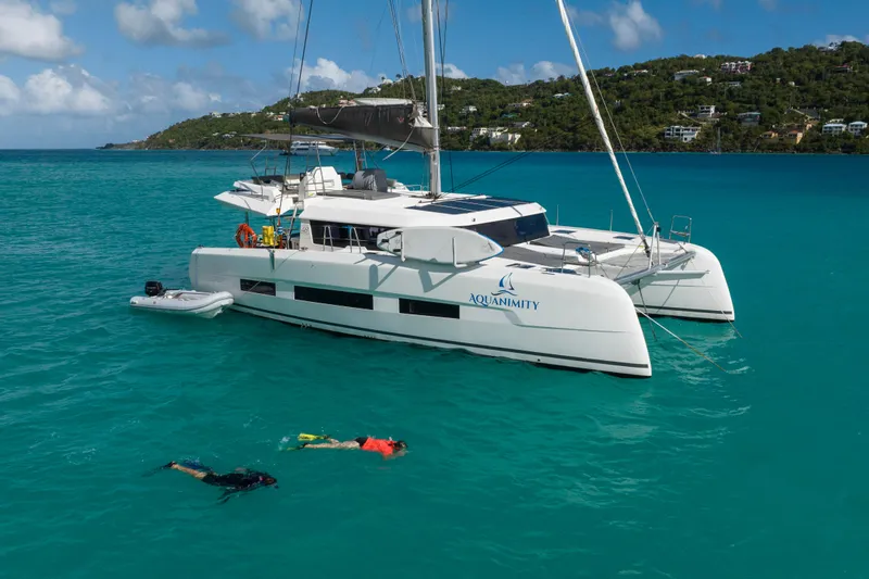 Aquanimity Yacht Photos Pics 2021 Dufour 48 catamaran "Aquanimity" anchored in turquoise waters with snorkelers nearby.