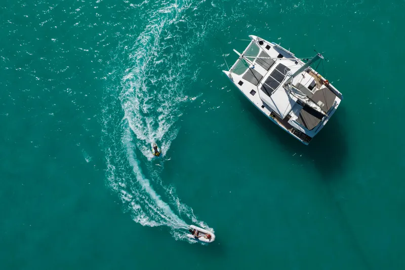 Aquanimity Yacht Photos Pics Aerial view of 2021 Dufour 48 yacht with jet skis in turquoise water.