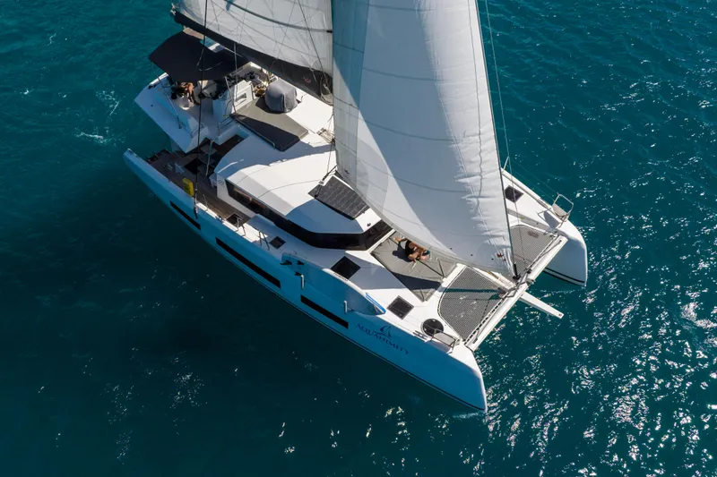 Aquanimity Yacht Photos Pics Aerial view of 2021 Dufour 48 catamaran sailing on clear blue water.