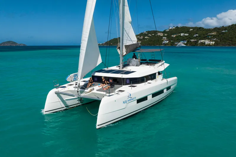 Aquanimity Yacht Photos Pics 2021 Dufour 48 catamaran sailing in turquoise waters near lush coastline.