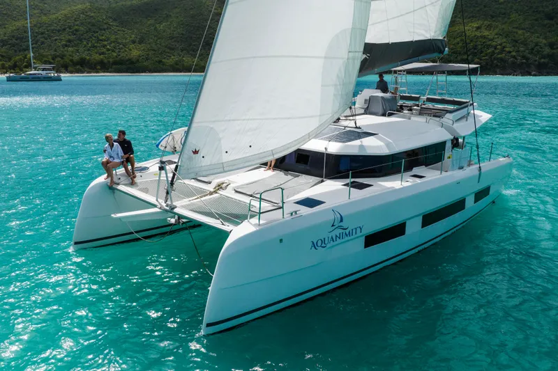 Aquanimity Yacht Photos Pics 2021 Dufour 48 catamaran sailing on turquoise waters with two people on deck.