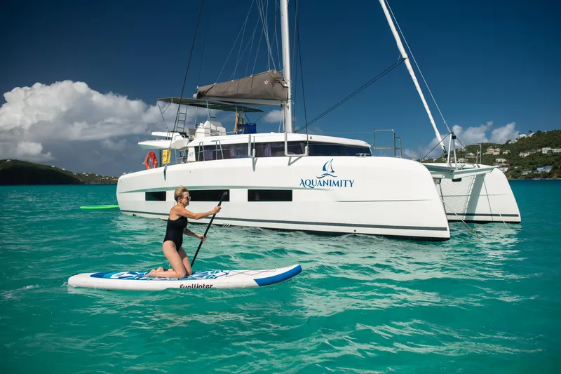 Aquanimity Yacht Photos Pics Woman paddleboarding near 2021 Dufour 48 catamaran "Aquanimity" in turquoise waters.