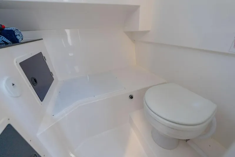  Yacht Photos Pics Compact bathroom in 2025 SeaWell 345XL boat, featuring a white toilet and storage compartment.