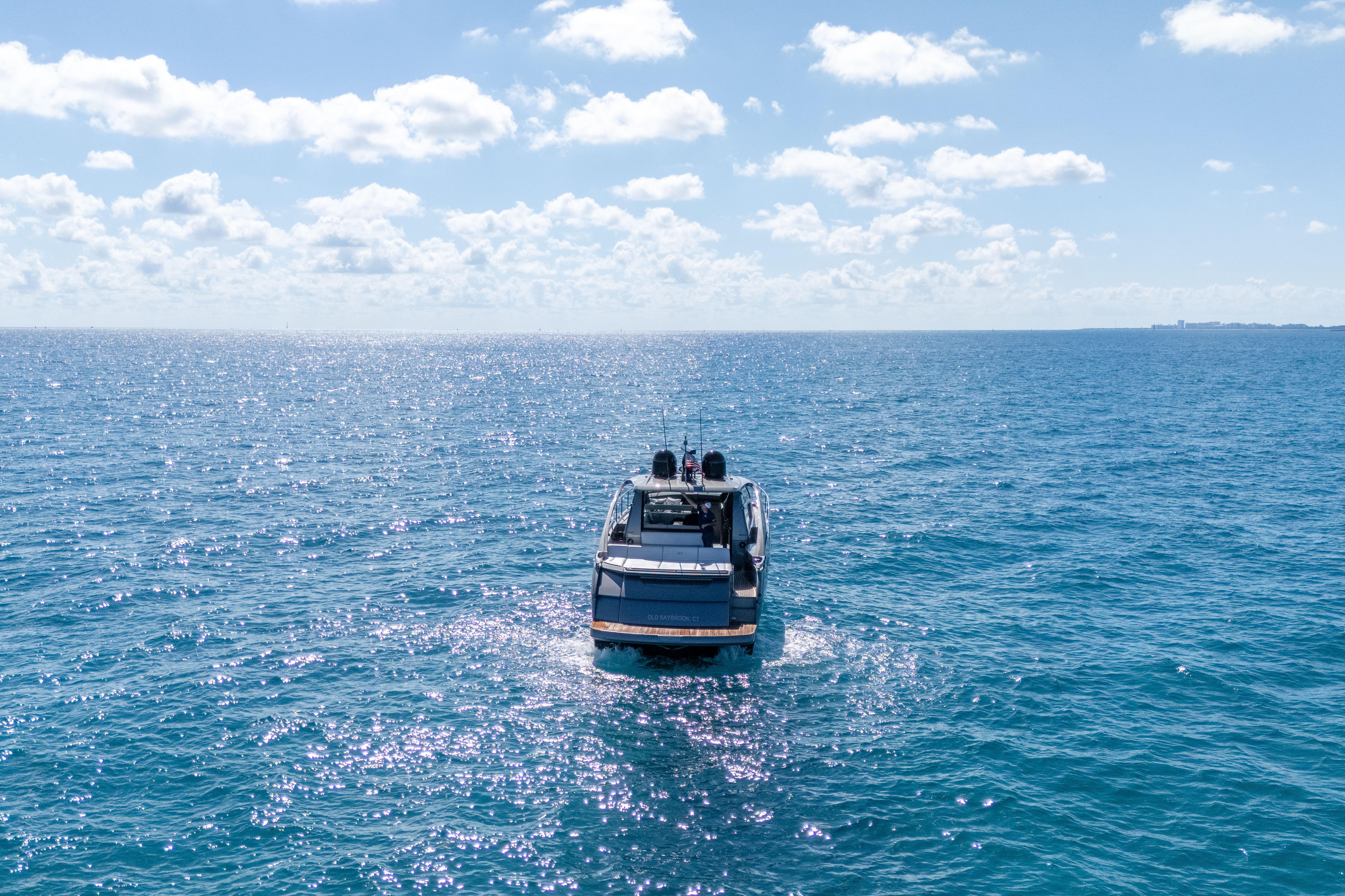 2019 Pershing 5x yacht cruising on open ocean under clear blue sky.