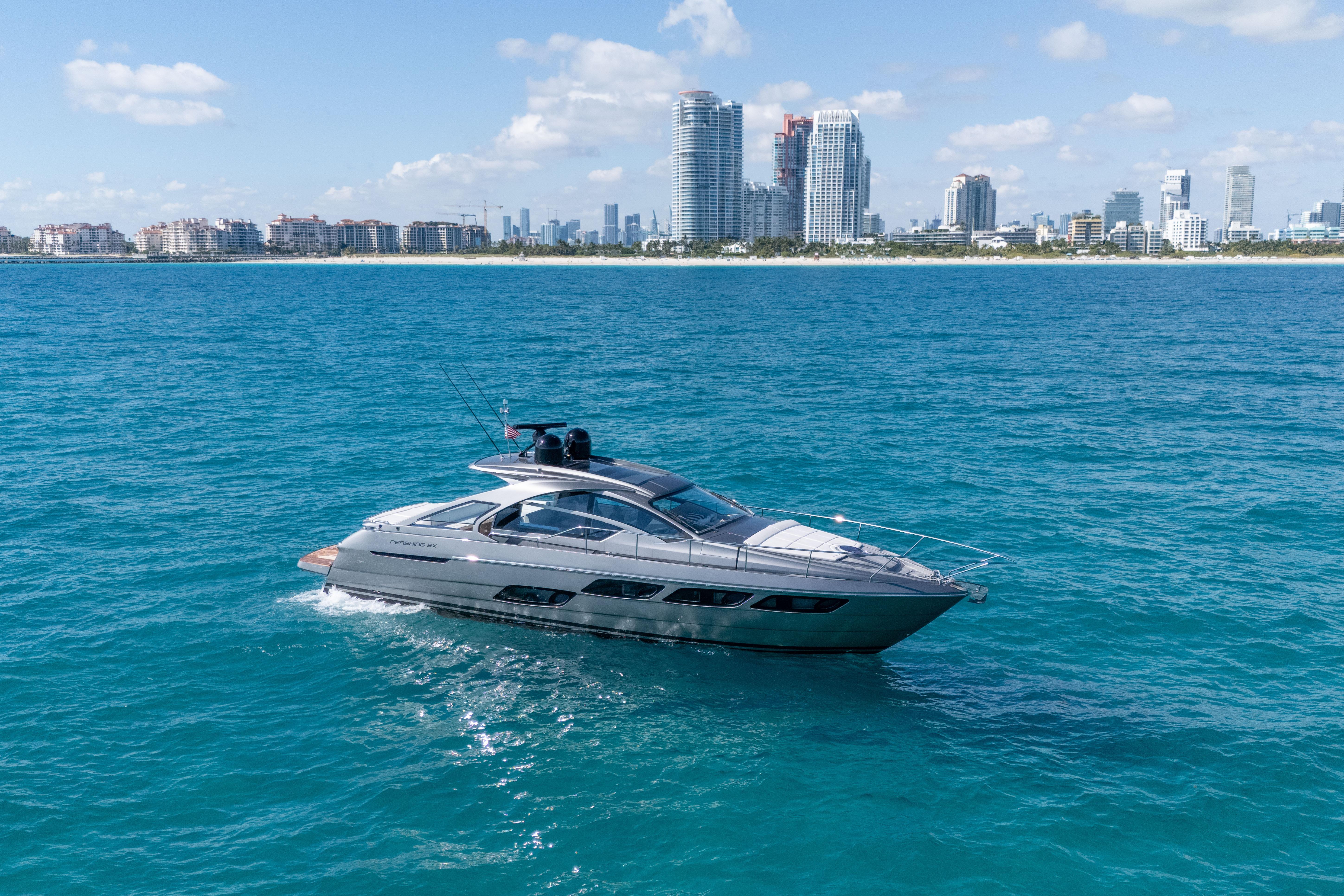 2019 Pershing 5x yacht cruising near city skyline on a sunny day.