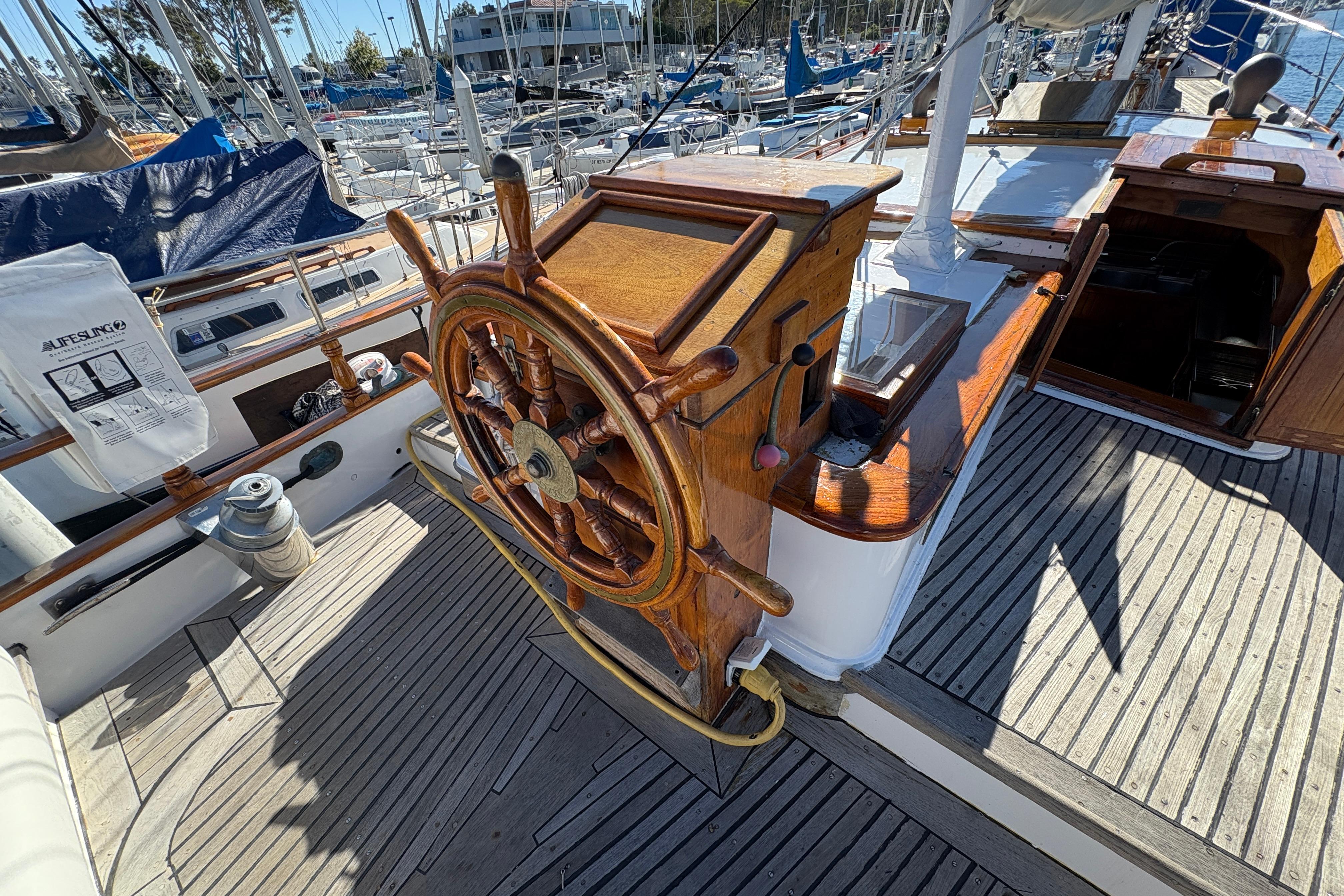 Wooden helm of a 1979 Formosa 51 sailboat, docked in a marina.