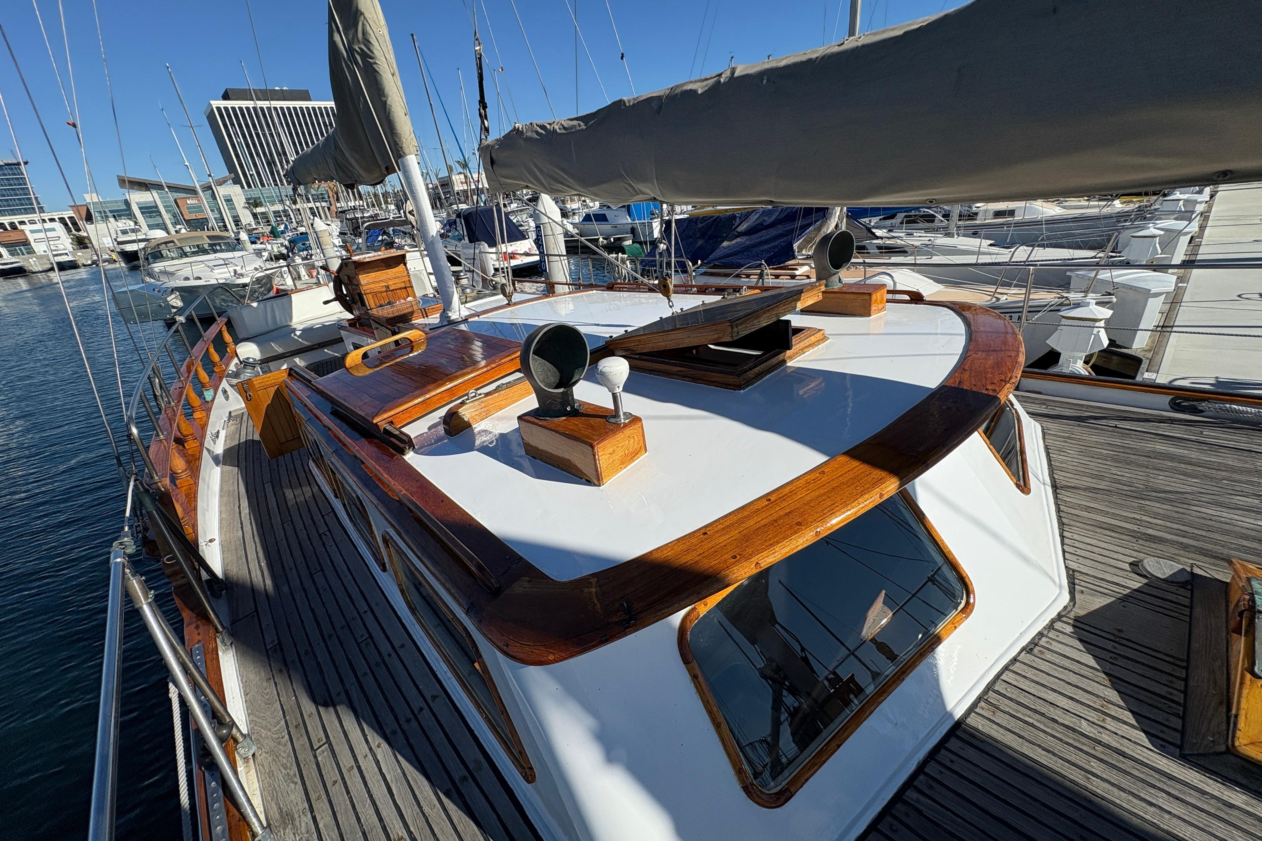 1979 Formosa 51 sailboat with wooden deck, docked in a marina under clear blue skies.
