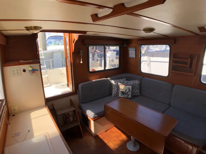  Yacht Photos Pics Cozy interior of 1989 Nordic Tug 32 with seating and table, featuring wood accents.