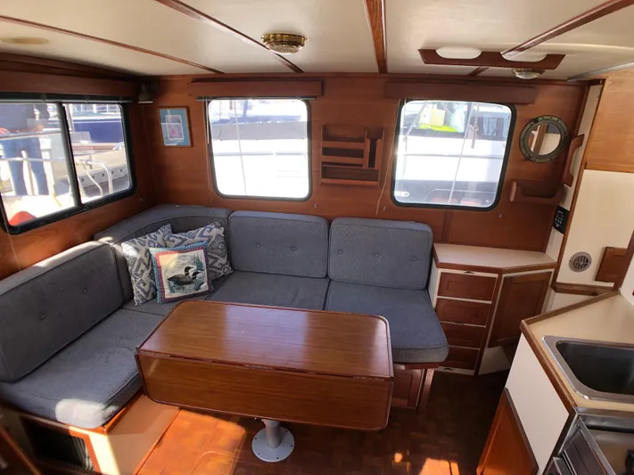  Yacht Photos Pics Cozy interior of 1989 Nordic Tug 32 with wooden furnishings and cushioned seating.