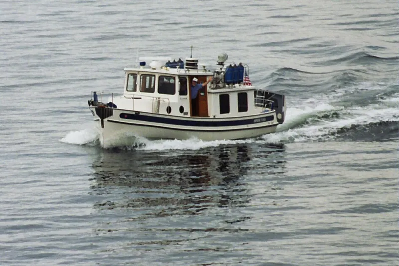  Yacht Photos Pics 1989 Nordic Tug 32 cruising on calm waters, showcasing classic design and sturdy build.