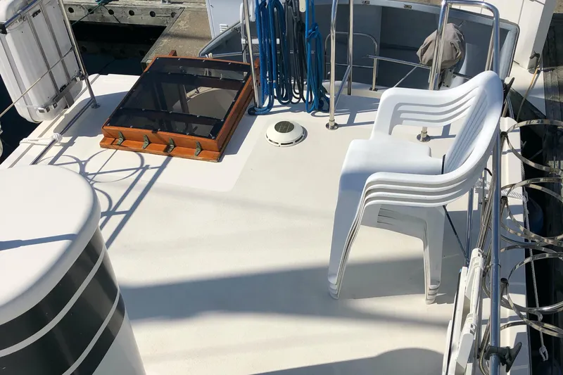  Yacht Photos Pics Nordic Tug 32 (1989) deck with stacked white chairs and nautical equipment.