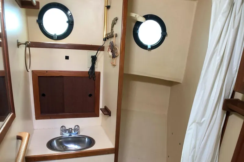  Yacht Photos Pics 1989 Nordic Tug 32 bathroom with portholes, sink, and wooden cabinetry.