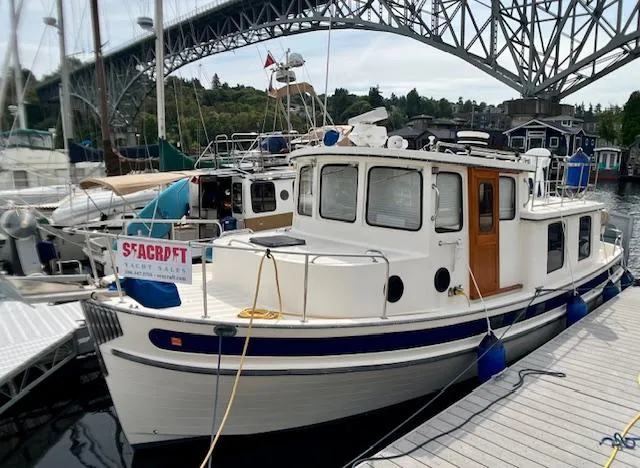  Yacht Photos Pics 1989 Nordic Tug 32 docked near a bridge, showcasing classic design and sturdy build.