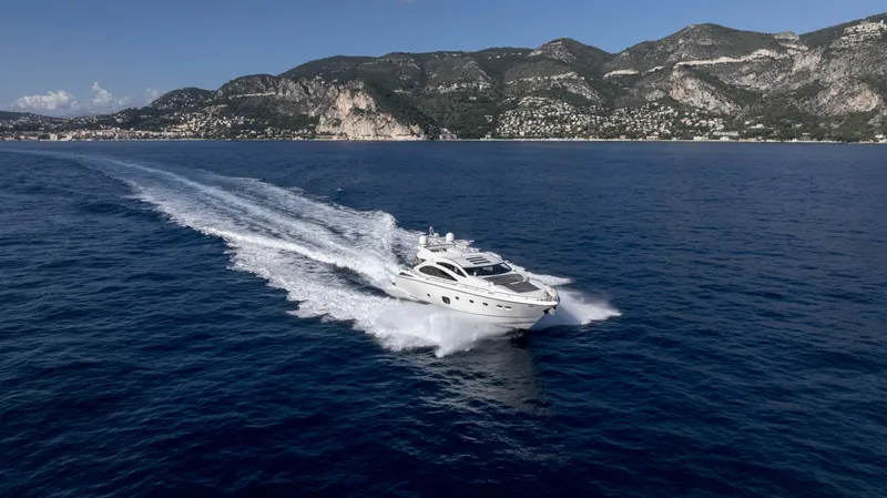 P'ocean Yacht Photos Pics Sunseeker Predator 84 yacht cruising on open sea, 2009 model, with scenic mountain backdrop.