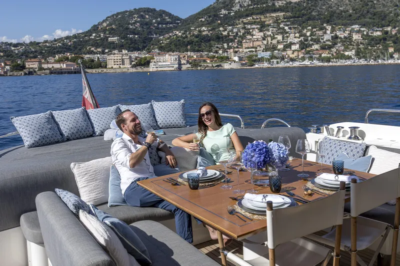 P'ocean Yacht Photos Pics Couple enjoying a meal on a 2009 Sunseeker Predator 84 yacht, scenic coastal backdrop.