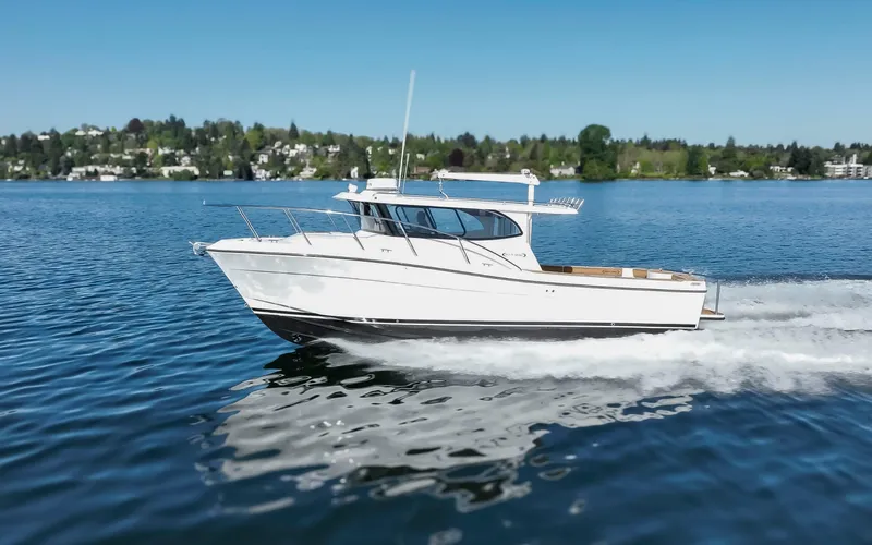  Yacht Photos Pics 2025 Ocean Sport Roamer cruising on a serene lake under a clear blue sky.
