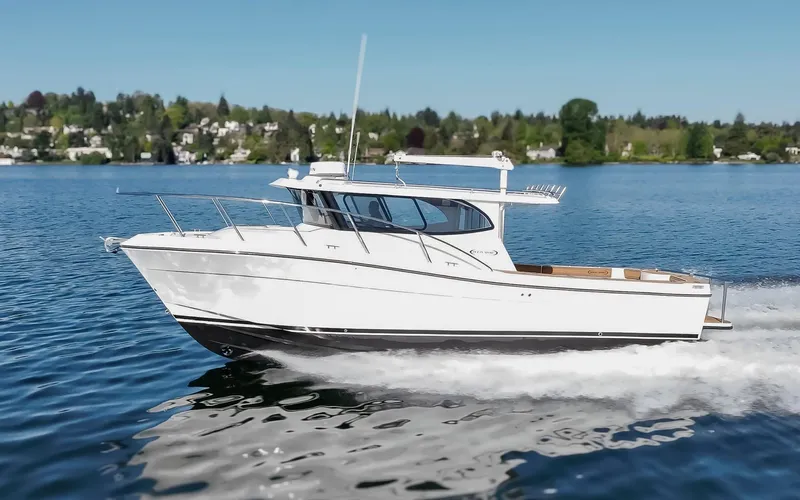  Yacht Photos Pics 2025 Ocean Sport Roamer cruising on a serene lake under a clear blue sky.