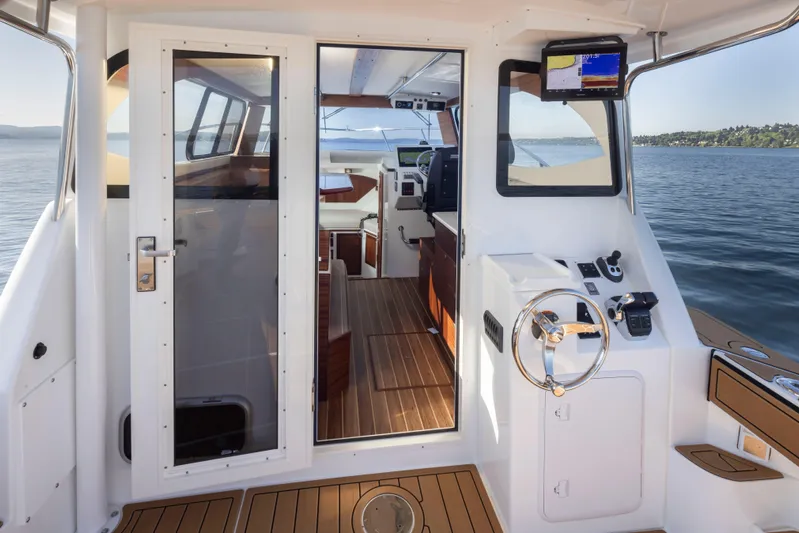  Yacht Photos Pics 2025 Ocean Sport Roamer boat interior with steering wheel, navigation equipment, and wooden flooring.