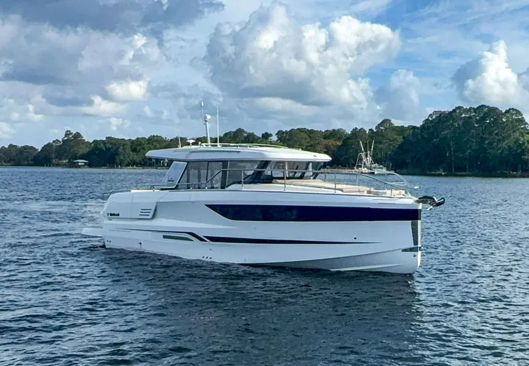  Yacht Photos Pics 2025 Wellcraft 44 Explorer yacht cruising on a serene lake under a partly cloudy sky.