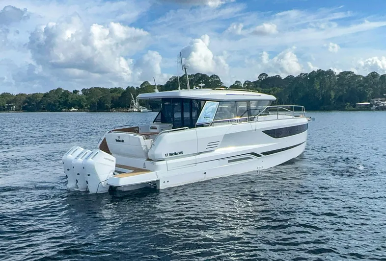  Yacht Photos Pics 2025 Wellcraft 44 Explorer boat cruising on a serene lake.