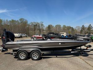 2012 Triton 21 HP boat on trailer in outdoor lot, surrounded by trees and other boats.