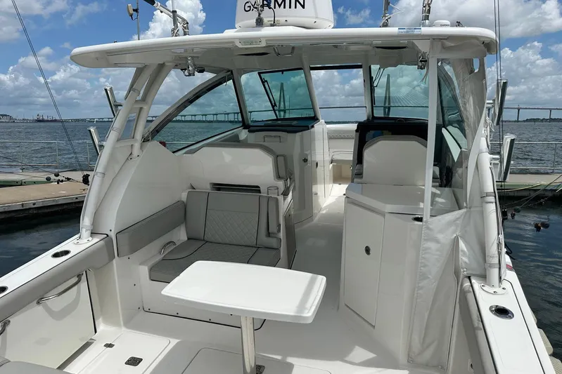 Sheminem Yacht Photos Pics 2023 Pursuit DC 295 Dual Console boat interior with seating and table, docked by the water.