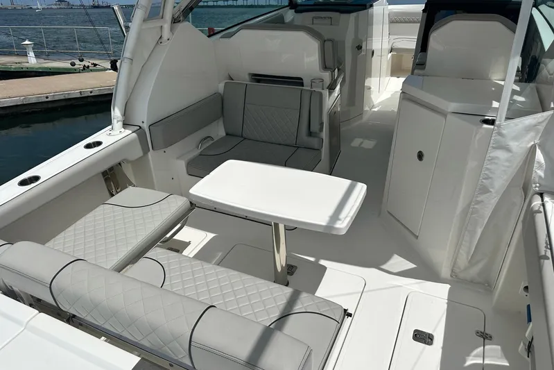 Sheminem Yacht Photos Pics 2023 Pursuit DC 295 Dual Console boat interior with seating and table, docked by the water.