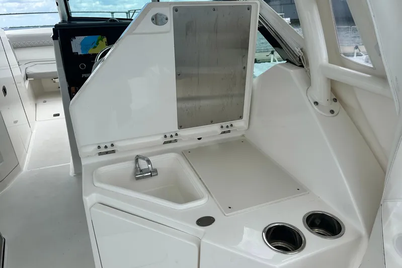 Sheminem Yacht Photos Pics 2023 Pursuit DC 295 Dual Console boat interior with sink and storage area.