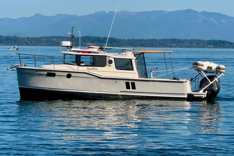 Noodles Yacht Photos Pics 2024 Ranger Tugs R-27 boat on calm water with scenic mountain backdrop.