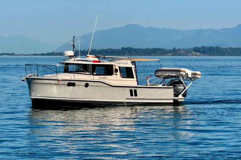 Noodles Yacht Photos Pics 2024 Ranger Tugs R-27 boat on calm water with scenic mountain backdrop.