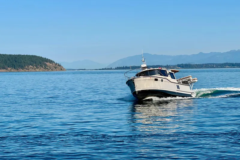 Noodles Yacht Photos Pics 2024 Ranger Tugs R-27 cruising on a serene blue lake with distant forested hills.