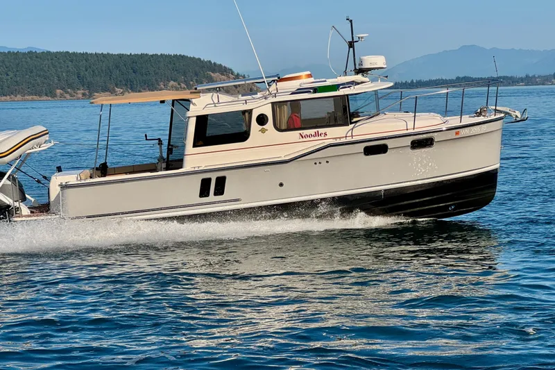 Noodles Yacht Photos Pics 2024 Ranger Tugs R-27 cruising on a scenic lake with forested hills in the background.