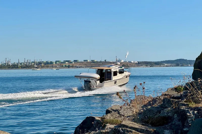 Noodles Yacht Photos Pics 2024 Ranger Tugs R-27 cruising on a sunny day near rocky shoreline.