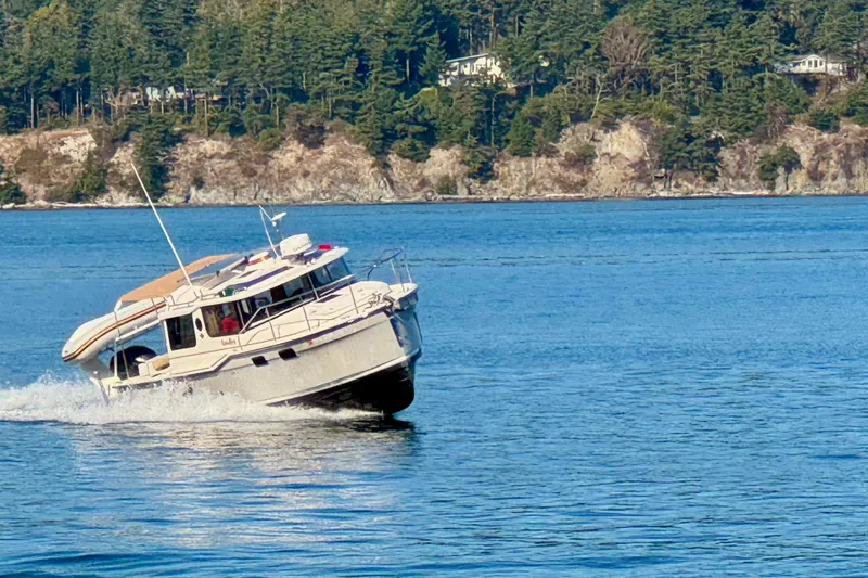 Noodles Yacht Photos Pics 2024 Ranger Tugs R-27 cruising on a scenic lake with forested shoreline.